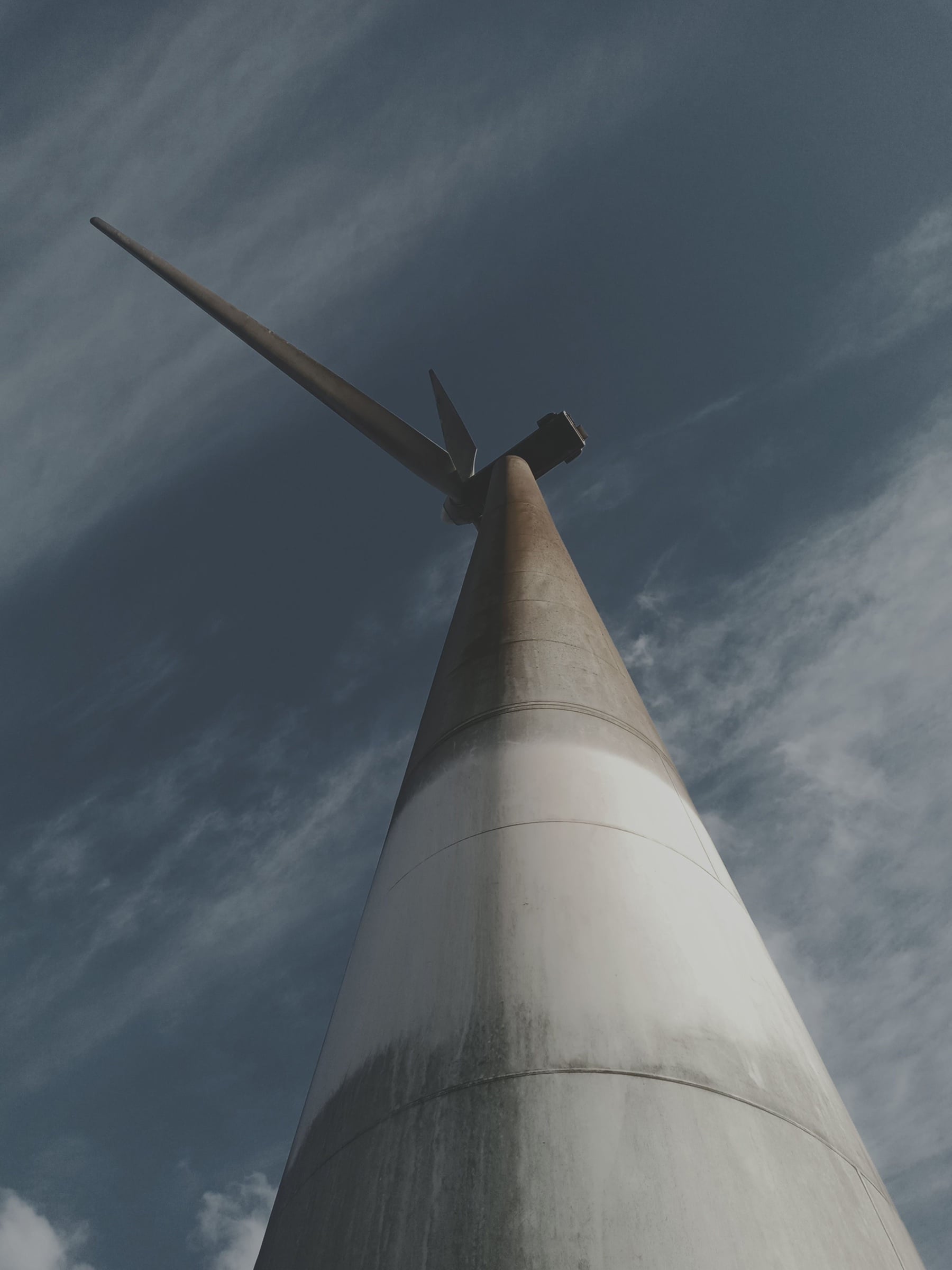 A wind turbine in Ngong, Kenya, seen from its base against a blue sky with high cloud.